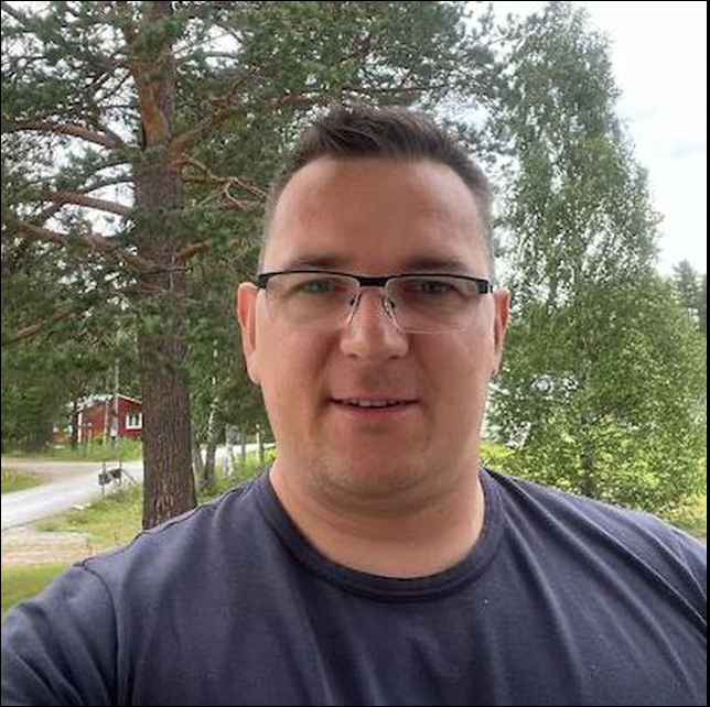 Professional woman with blonde hair in navy blazer smiling confidently in modern office